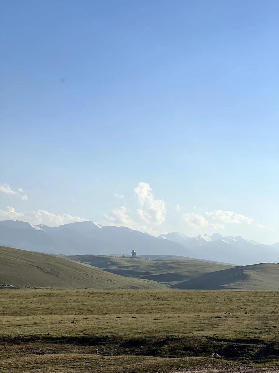 Vast grassy plateau stretching toward distant snow-capped mountains on the horizon